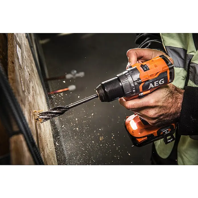 AEG Pro 18V Akku-Bohrschrauber BS18SBL2-202C - 18 V, 2 Akkus, 2 Ah, 60 Nm - Nahaufnahme einer AEG Akku-Bohrmaschine beim Bohren in ein Holzstück, Späne fliegen umher. Der Fokus liegt auf der Leistung und Präzision des Werkzeugs.