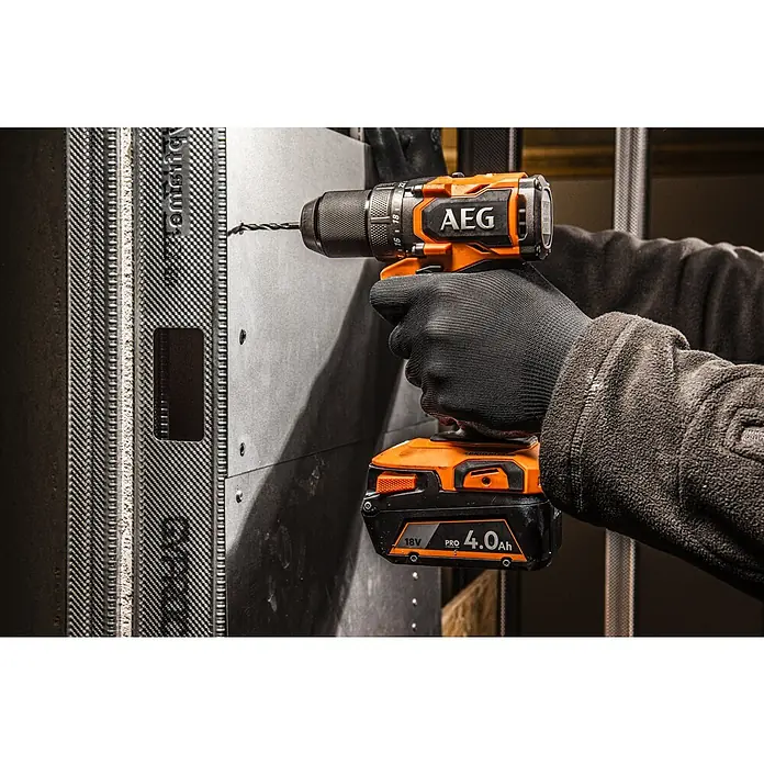 AEG Pro 18V Akku-Bohrschrauber BS18SBL2-202C - 18 V, 2 Akkus, 2 Ah, 60 Nm - Nahaufnahme einer AEG Bohrmaschine mit einem 18V 4.0Ah Akku, die in eine graue Wand bohrt, gehalten von einer Hand mit schwarzem Handschuh.