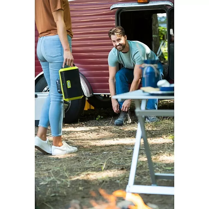Ryobi ONE+ Altavoz Bluetooth RBT18-0 - 18 V, Sin batería, Potencia de salida altavoz: 15 W - Estación de energía/altavoz portátil amarillo y negro, sujetado por mujer en un camping.