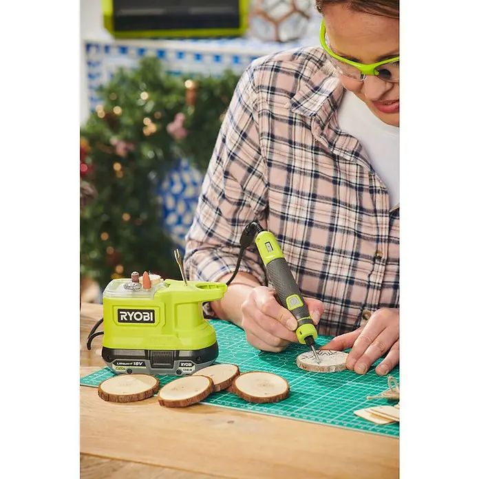 Ryobi ONE+ Akku-Multifunktionswerkzeug RRT18-0 - 18 V, Ohne Akku, Leerlaufdrehzahl: 4.400 U/min - 23.000 U/min - Eine Frau, die mit einem RYOBI-Schleifwerkzeug Holzscheiben bearbeitet, um festliche Ornamente zu erstellen.