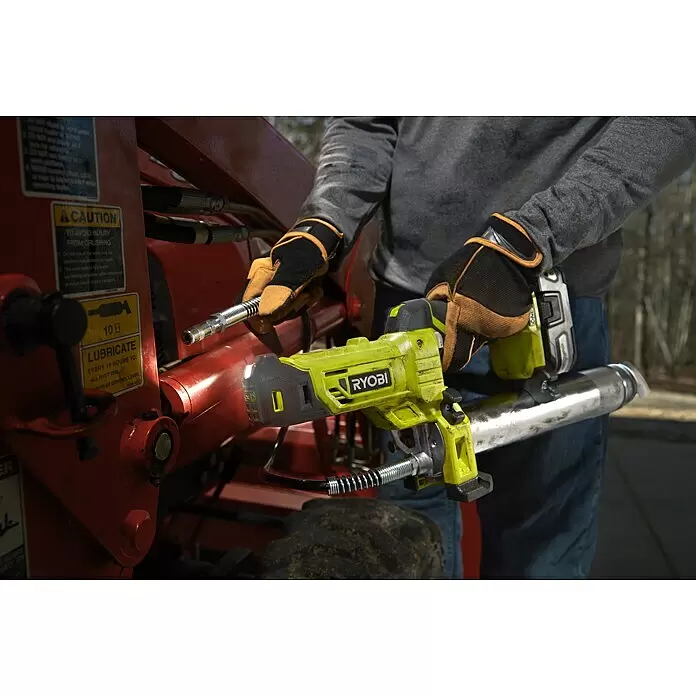 Ryobi ONE+ Akku-Fettpresse R18GG-0 - 18 V, Ohne Akku, Li-Ionen, Max. Druck: 690 bar - Person schmiert mit einer gelb-schwarzen Ryobi Fettpresse rote Baumaschinen.