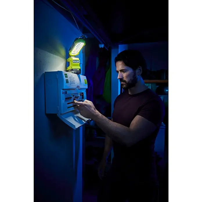 Ryobi ONE+ LED-Arbeitsleuchte R18ALP-0 - 18 V, Li-Ionen, Ohne Akku, 900 lm - Ein Mann bedient einen Sicherungskasten mit einer tragbaren Ryobi-LED-Lampe, die für eine praktische Beleuchtung sorgt.