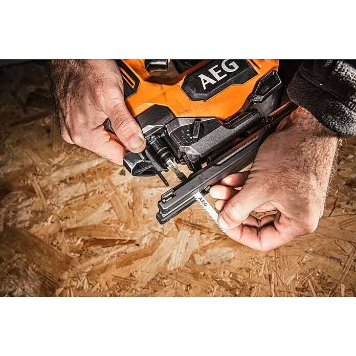 AEG Pro 18V Akku-Stichsäge BST 18BLX2-0 - 18 V, Ohne Akku, Leerlaufhubzahl: 0 /min - 3.500 /min - Eine Person wechselt das Sägeblatt einer orange-schwarzen AEG Stichsäge.