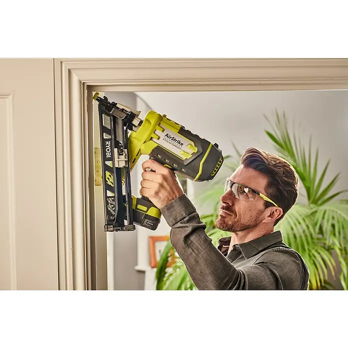 Ryobi ONE+ Akku-Nagler R15GN18-0 - 18 V, Ohne Akku - Ein Mann benutzt einen Ryobi AirStrike Nagler, um Türrahmen zu befestigen, und trägt dabei eine Schutzbrille für mehr Sicherheit.