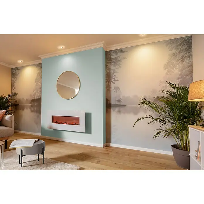 swingcolor Soft Colors WandfarbeAloe, Matt, 5 l - Ein modernes Wohnzimmer mit einem weißen elektrischen Kamin an einer mintgrünen Wand, darüber ein runder Spiegel, der das gemütliche Ambiente hervorhebt.
