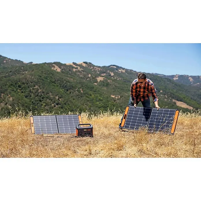 Jackery Colector luz solar Saga - 100 W, 122 x 53,5 cm - Un hombre instala paneles solares Jackery en el exterior para generar energía para una central eléctrica portátil Jackery.