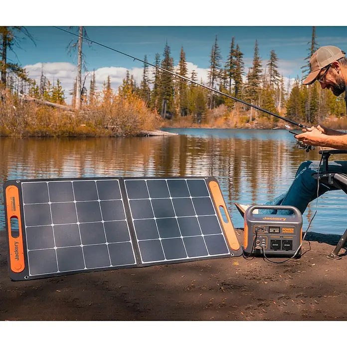 Jackery Colector luz solar Saga - 100 W, 122 x 53,5 cm - El generador solar Jackery con panel carga la estación de energía portátil, mientras un pescador se relaja en el lago.