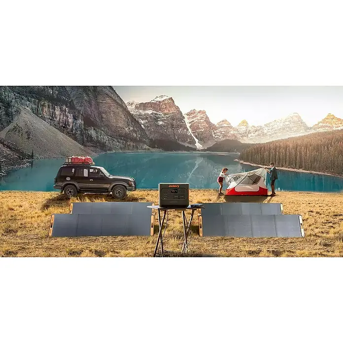 Jackery Estación de energía portátil Explorer 1000 Pro EU - 1.000 Wh, Negro, 23,3 Ah - Una estación de energía Jackery y un panel solar para acampar, con una tienda y un todoterreno con un fondo montañoso.
