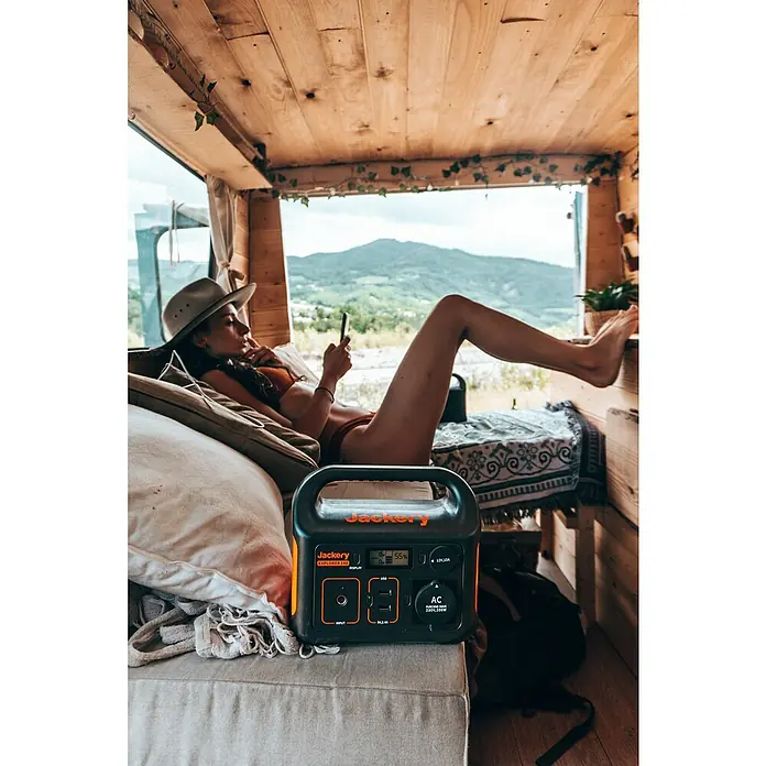 Jackery Estación de energía portátil Explorer 240 Pro EU - 240 Wh, Negro, 16,8 Ah - Una estación de energía Jackery Explorer 240 en primer plano, con una mujer relajándose en el fondo. Ideal para camping y actividades al aire libre.