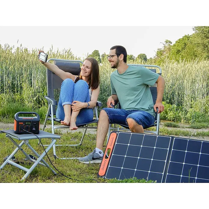 Jackery Estación de energía portátil Explorer 240 Pro EU - 240 Wh, Negro, 16,8 Ah - Una pareja se relaja al aire libre con una estación de energía Jackery y un panel solar para soluciones de energía ecológica.