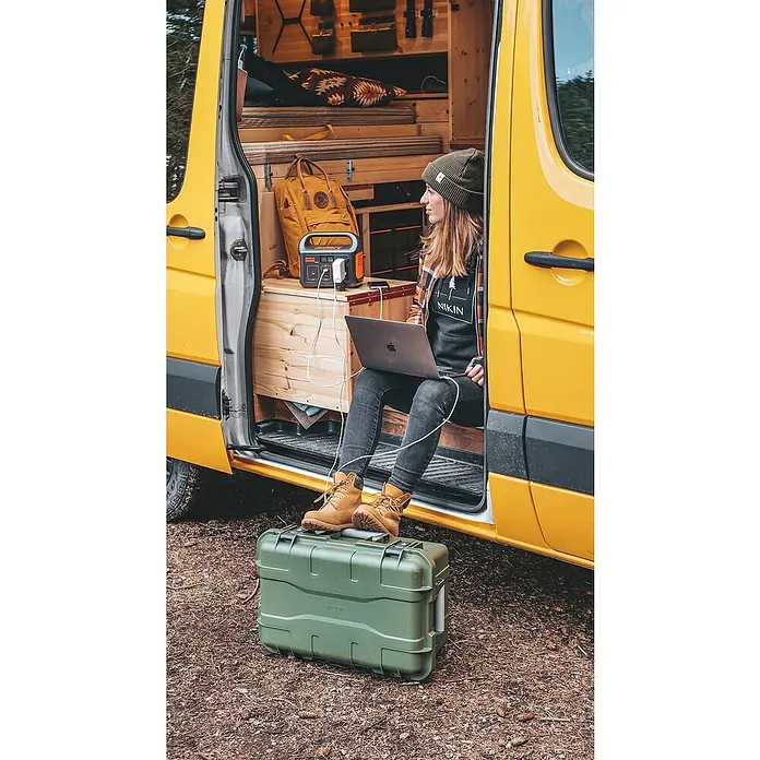 Jackery Estación de energía portátil Explorer 240 Pro EU - 240 Wh, Negro, 16,8 Ah - Mujer con computadora portátil, estación de energía Jackery cargando en una camioneta amarilla. Perfecto para aventuras al aire libre!