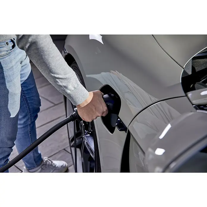 AEG Kfz-Ladekabel Schuko-Stecker zu Typ 2 Stecker - Kabellänge: 7 m - Ein helles Elektroauto wird von einer Person mit einem schwarzen Ladekabel aufgeladen. Fokus liegt auf dem Ladevorgang des Fahrzeugs.