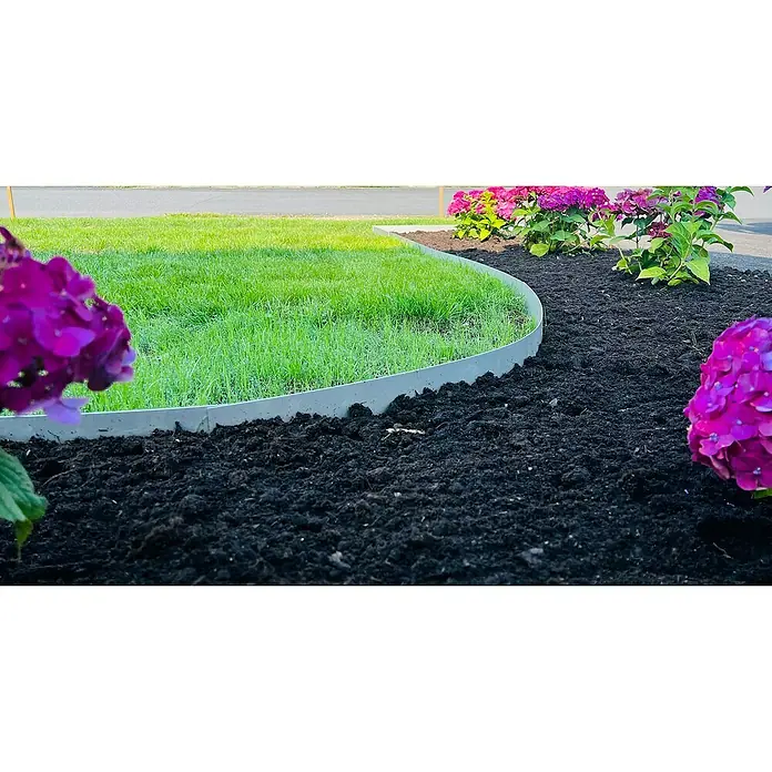 Recal Rasenkante Recal - 1.100 x 1,6 x 100 mm, Silber, Metall - Das Foto zeigt Rasenkanten aus grauem Kunststoff, die einen Rasen von einem Beet mit Mulch und rosa Hortensien trennen.