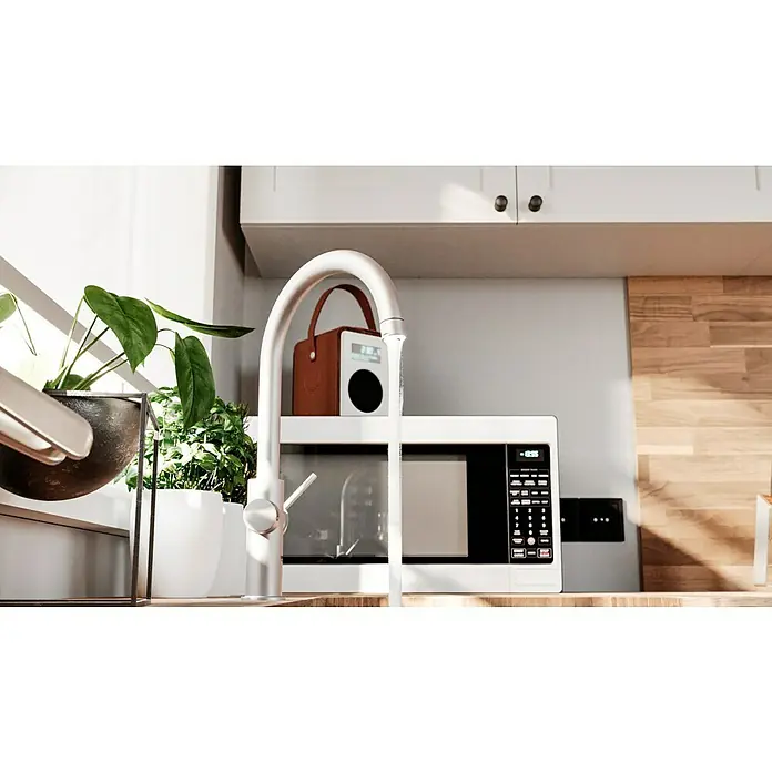 Grohe Spültischarmatur Blue Home - Höhe: 41,8 cm, C-Auslauf, Supersteel, Matt, Schwenkbar - Nahaufnahme einer modernen Küche mit einem weißen Wasserhahn, der Wasser liefert, und einem weißen Mikrowellenherd darunter.