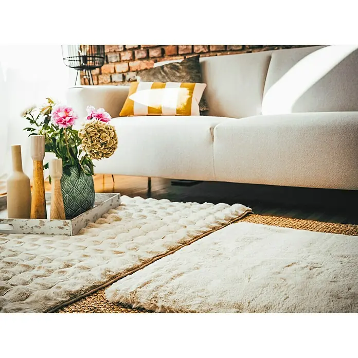 Alfombra de pelo largo Harmony - Beige, 170 x 120 cm, 100% Poliéster - Una acogedora sala de estar con un sofá color crema, una mesa de centro con decoración y una alfombra mullida para mayor calidez.