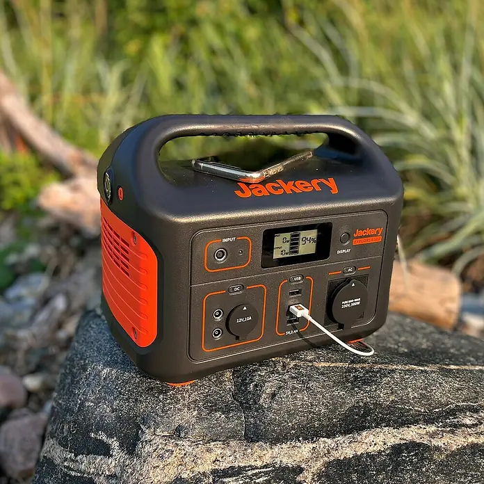 Jackery Estación de energía portátil Explorer 500 Pro EU - 500 Wh, Negro, 24 Ah - Central eléctrica Jackery Explorer 500 con pantalla, puertos y móvil sobre una roca en la naturaleza para alimentación independiente.