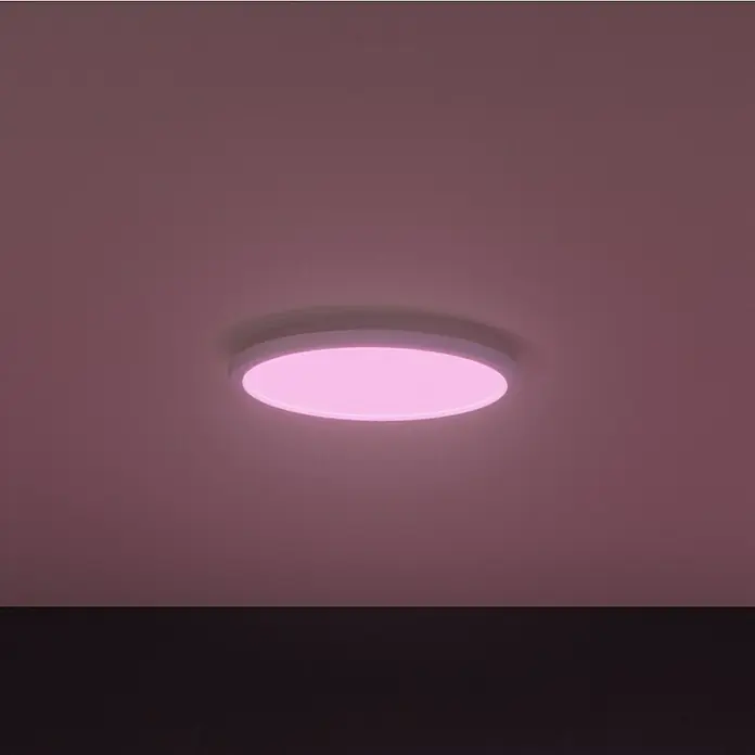 Philips Hue LED-Panel rund Surimu - 45 W, Ø x H: 395 x 4,7 cm, Weiß, Opal, RGBW - Nahaufnahme einer runden Deckenleuchte, die pinkfarbenes Licht ausstrahlt und eine warme und moderne Atmosphäre erzeugt.