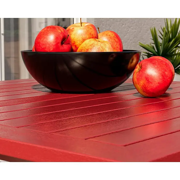 swingcolor Buntlack Kunstharz für Außen - Feuerrot, Seidenmatt, 125 ml, Lösemittelbasiert - Eine Nahaufnahme einer Schale mit roten Äpfeln auf einem roten Holztisch mit einer Pflanze im Hintergrund.