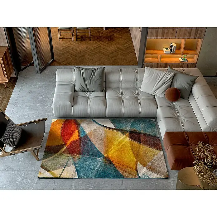 Alfombra de pelo corto Leire - Multicolor, 200 x 140 cm - Primer plano de una alfombra colorida con un diseño abstracto, colocada debajo de un moderno sofá gris en una sala de estar elegante.