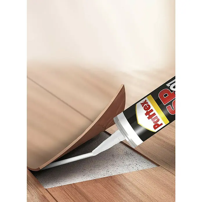 Pattex Sellador SP 101 - Marrón, 300 ml - Primer plano de un cartucho Pattex aplicando sellador entre un zócalo y un pavimento, ideal para trabajos de sellado.