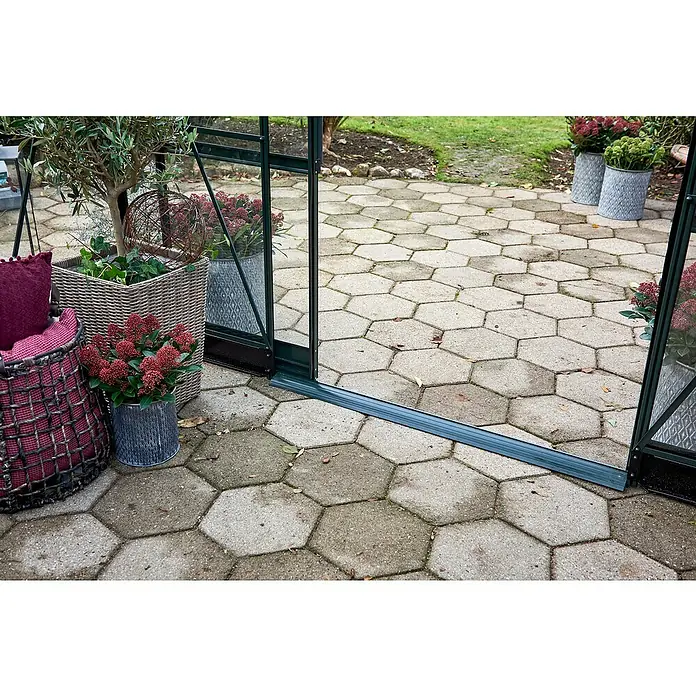 Halls Gewächshaus Icon Gardenhouse - Außenmaß inkl. Dachüberstand (B x T): 383,9 x 381,5 cm, Material Seitenwand: Glas, 3 mm, Schwarz - Nahaufnahme eines Gartens mit sechseckigen Pflastersteinen und Topfpflanzen, die eine idyllische Szene im Freien zeigen.