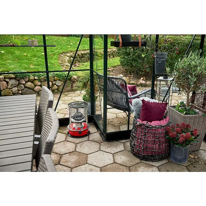 Halls Gewächshaus Garden Room - Außenmaß inkl. Dachüberstand (B x T): 390 x 389 cm, Material Seitenwand: Glas, 3 mm, Grün - Diese Aufnahme zeigt einen roten Petroleumofen, der Wärme und Gemütlichkeit in den Wintergarten bringt. Dekorative Körbe & Sitzmöbel vervollständigen das Bild.