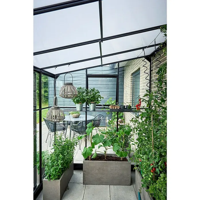 Halls Qube Gewächshaus Lean-to 612 - Außenmaß inkl. Dachüberstand (B x T): 374 x 188 cm, Material Seitenwand: Glas, 3 mm, Schwarz - Das Bild zeigt ein Gewächshaus mit Esstisch und Pflanzenkübeln. Die Pflanzenkübel enthalten Gemüse und Kräuter.