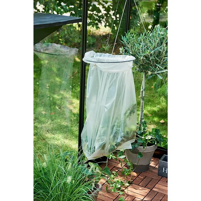 Juliana Ringhalter - Passend für: Halls und Juliana Gewächshäuser - Ein Pflanzgefäß mit einer transparenten Schutzhülle in einem Garten, umgeben von Grünpflanzen und Holzboden.