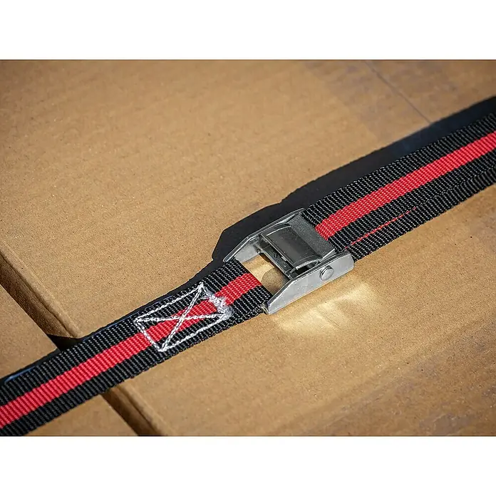LAS Spanngurt - 5 m x 2,5 cm - Nahaufnahme eines schwarzen und roten Gepäckgurtes mit Metallschnalle auf einem Karton, ideal zum Sichern von Gepäck.
