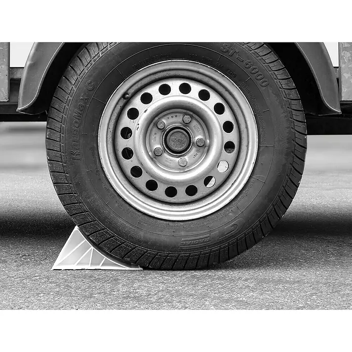 LAS Unterlegkeil - Max. zulässiges Gesamtgewicht: 1.600 kg - Ein schwarzer Reifen mit Radkeil auf Asphalt, der die Sicherheit und Stabilität des Fahrzeugs gewährleistet.