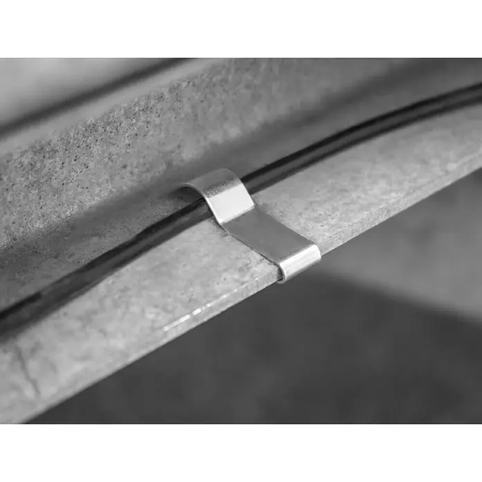 LAS Kabelklemme - 10 Stk. - Nahaufnahme einer Metallschelle, die ein schwarzes Kabel an einer grauen, strukturierten Oberfläche befestigt. Metallisch glänzend und robust.