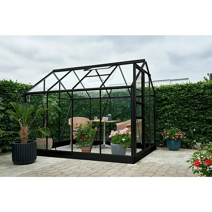 Halls Gewächshaus Popular 86 - Außenmaß inkl. Dachüberstand (B x T): 193 x 257 cm, Material Seitenwand: Glas, 3 mm, Schwarz - Ein elegantes, schwarzes Gewächshaus mit Glaswänden, umgeben von üppigem Grün und Blumen, lädt zum Verweilen im Garten ein.