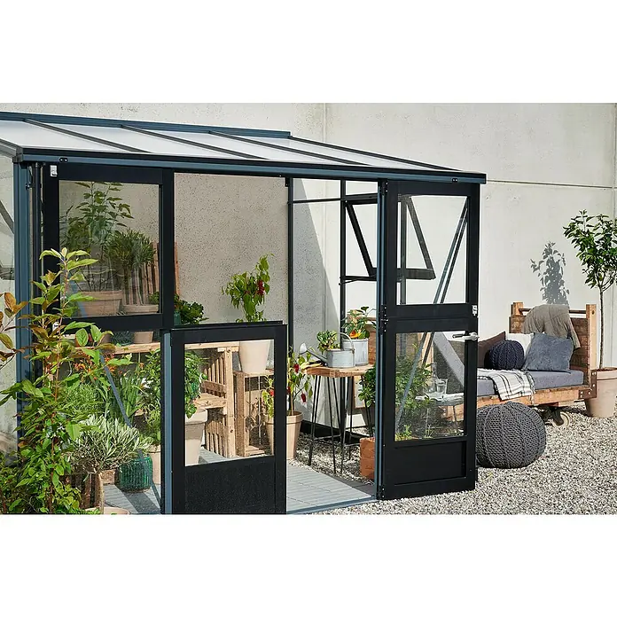 Juliana Gewächshaus Veranda - Außenmaß inkl. Dachüberstand (B x T): 221 x 296 cm, Material Seitenwand: Glas, 3 mm, Anthrazit - Einladendes Gewächshaus mit geöffneter Tür, gefüllt mit Pflanzen und gemütlicher Sitzecke im Außenbereich.