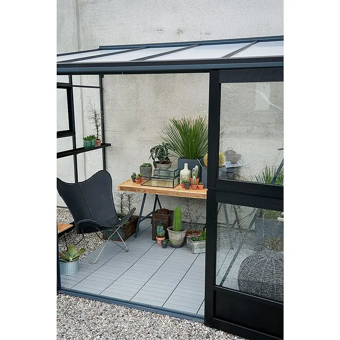 Juliana Gewächshaus Veranda - Außenmaß inkl. Dachüberstand (B x T): 221 x 296 cm, Material Seitenwand: Glas, 3 mm, Anthrazit - Einladendes Gewächshaus mit verschiedenen Pflanzen und einem eleganten Sessel. Der perfekte Ort zum Entspannen und Genießen.