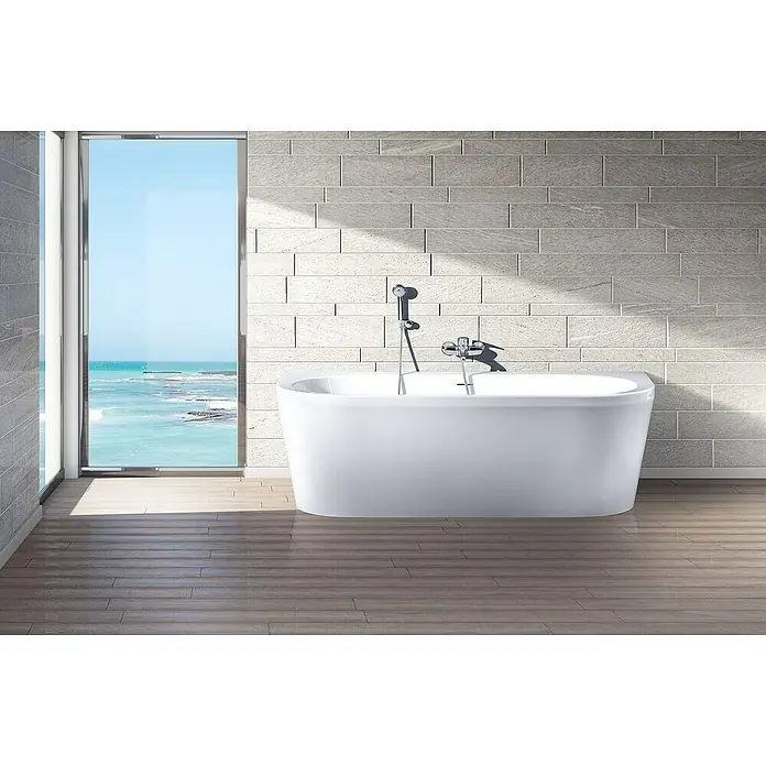 Ottofond Whirlpool Siesta180 x 79 cm, Sanitäracryl, Weiß, Silent - Elegantes Badezimmer mit freistehender Badewanne und Meerblick durch das große Fenster. Die Badewanne ist der zentrale Fokus.