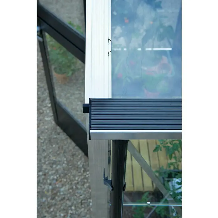 Juliana Gewächshaus Compact - Außenmaß inkl. Dachüberstand (B x T): 224 x 295 cm, Material Seitenwand: Glas, 3 mm, Silber/Schwarz - Nahaufnahme eines Gewächshausfensters mit Lamellen, das das Pflanzenwachstum und das Tageslichtmanagement zeigt.