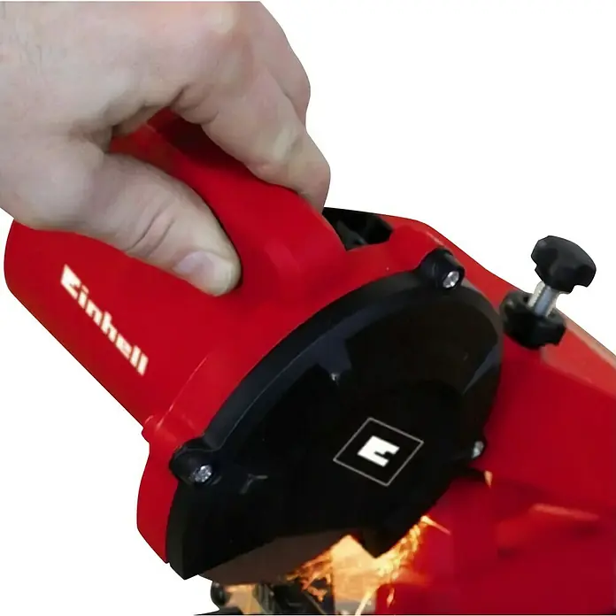 Einhell Sägekettenschärfgerät GC-CS 85 E - Mit Tiefenbegrenzung, Kettenspannvorrichtung, inklusive Schleifscheibe - Nahaufnahme einer roten Einhell-Trennschleifmaschine, die von einer Hand bedient wird und beim Schneiden von Metall Funken sprüht.
