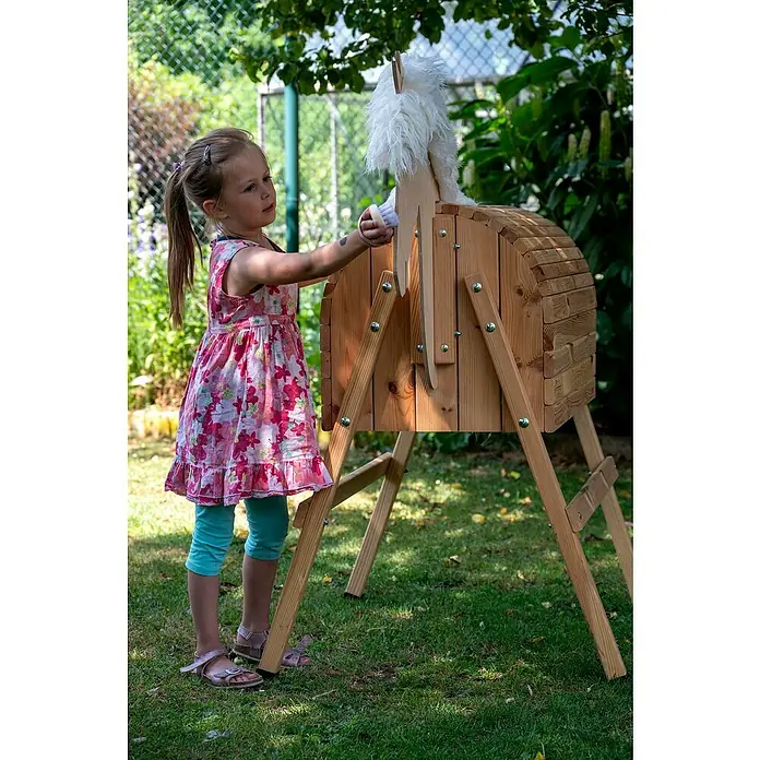 Dobar Holzpferd Bravido - L x B x H: 139 x 78 x 146 cm, Altersempfehlung: 3 Jahre - Mädchen bürstet liebevoll das Fell eines Holzpferdes in ihrem Garten. Ein idyllischer und spielerischer Moment.