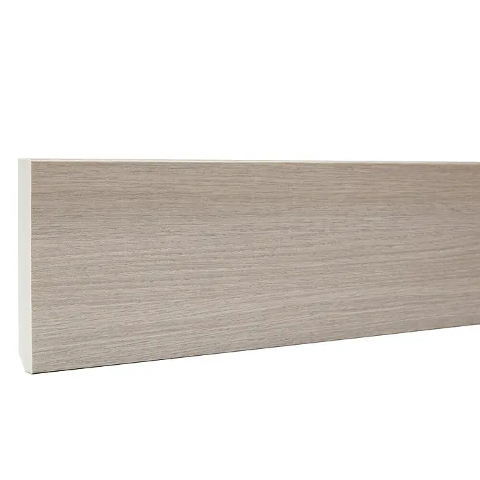 Rodapié espumado Gotham Argento - 2,2 x 13 x 90 mm - Se muestra un zócalo de aspecto de madera clara con un borde blanco sobre un fondo negro, utilizado como un acabado decorativo donde la pared se encuentra con el suelo.