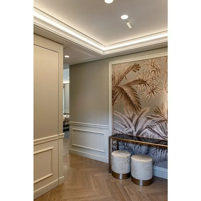 Nmc Decoflair Zierprofil Deckenleiste Z16 - 2 m x 50 mm x 70 mm, Hochverdichteter Polyurethanschaum (PU) - Innenaufnahme eines eleganten Raumes mit Wandbild, Konsole, Hockern und Fischgrätparkett, beleuchtet durch moderne Deckenleuchten.