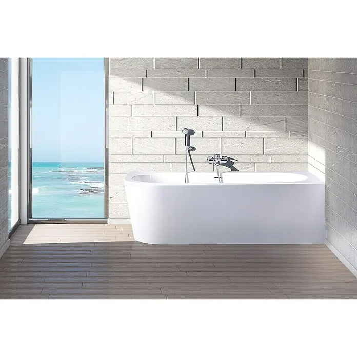 Ottofond Whirlpool Siesta Corner - 178 x 78 cm, Sanitäracryl, Weiß, Light/Silent, Linksseitig - Weisse Badewanne vor einem Fenster mit Meerblick. Die Badewanne hat eine moderne Armatur und eine Handbrause. Perfekt für entspannende Bäder!