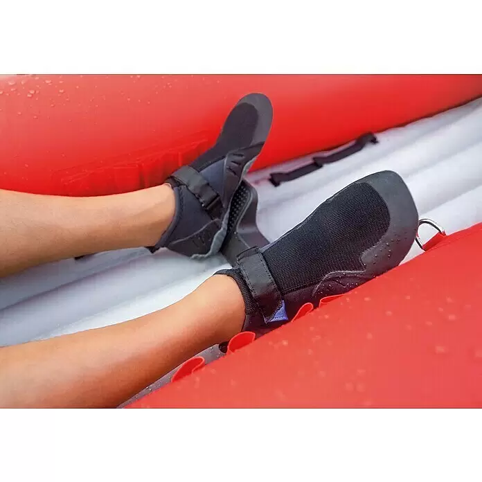 Intex Kajak Komplettset Excursion Pro - Nutzlast: 180 kg, Geeignet für: 2 Personen - Füße tragen schwarze Wasserschuhe mit verstellbaren Riemen in einem nassen rot-weißen Schlauchboot.