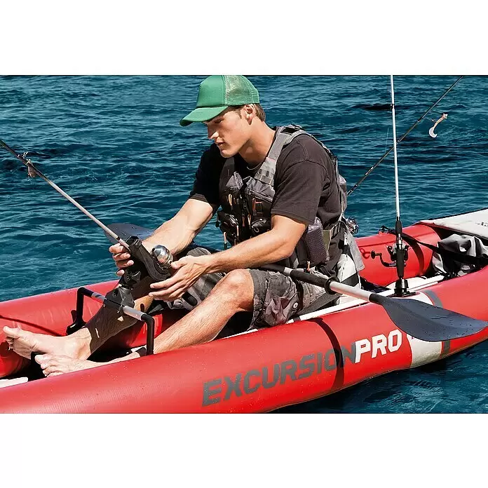 Intex Kajak Komplettset Excursion Pro - Nutzlast: 180 kg, Geeignet für: 2 Personen - Rotes, aufblasbares Angelkajak mit sitzendem Mann, der eine Angelrute hält. „EXCURSION PRO“ an der Seite sichtbar.