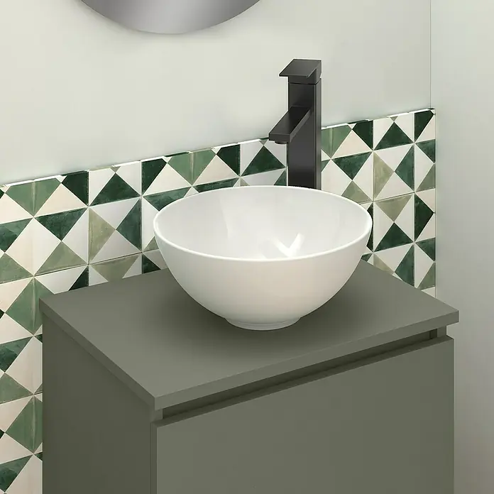Artysan Conjunto de mueble de baño Nuca - Ancho: 45 cm, Verde Musgo, 3 pzs. - Un lavabo sobre encimera blanco se asienta sobre un tocador gris con un grifo. Azulejos triangulares en tonos verdes y blancos en el fondo.