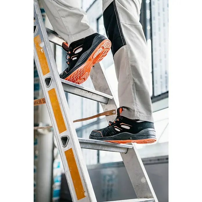 Sicherheitshalbschuh Tony - 42, Schutzklasse nach EN ISO 20345: S1P, Schwarz, Orange - Eine Person steigt eine Leiter mit schwarzen und orangefarbenen Sicherheitsschuhen hinauf. Diese Schuhe bieten Schutz und Komfort.