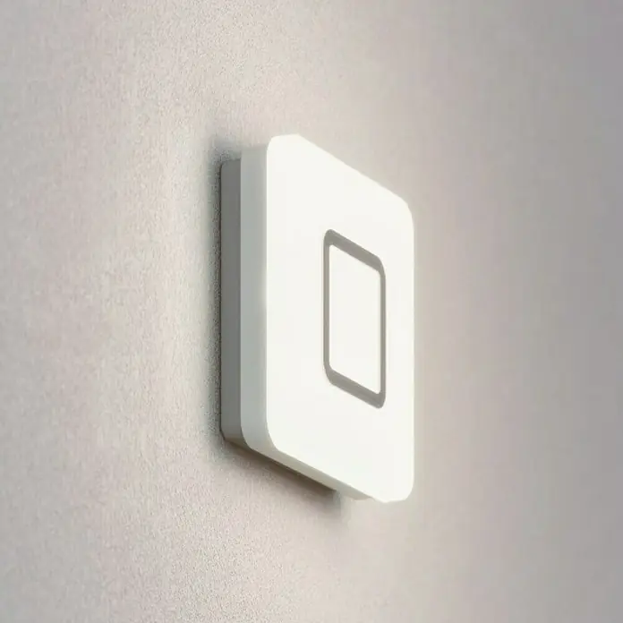 Steinel Sensor-Wand- & Deckenleuchte RS LED M1 S Edelstahl - 8,8 W, L x B x H: 20 x 20 x 5,3 cm, Weiß - Nahaufnahme eines quadratischen, beleuchteten Wandschalters mit einem viereckigen Symbol in der Mitte.