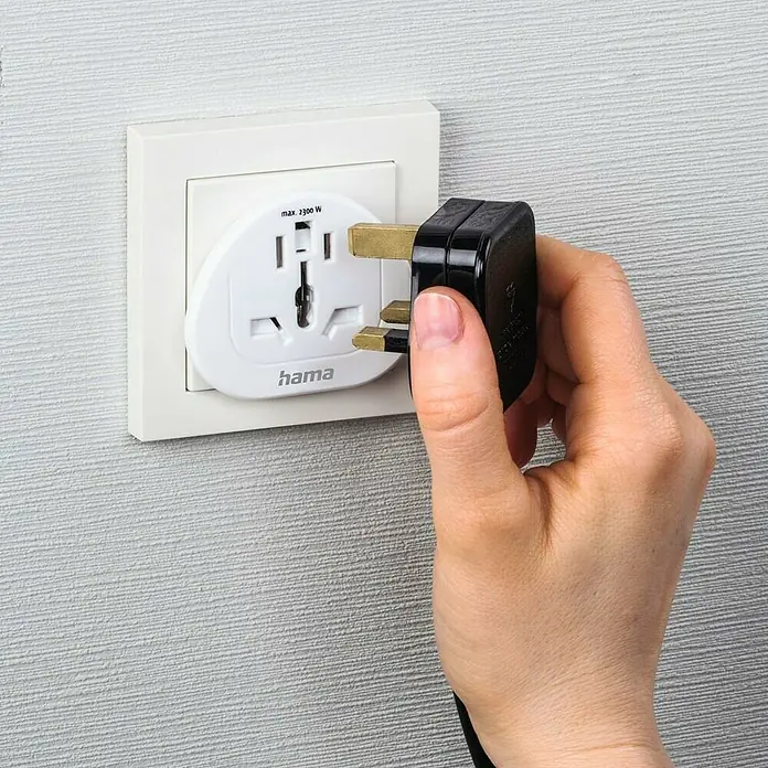 Hama Reiseadapter Welt nach Europa - Netzsteckertyp Reiseadapter: Typ E+F (CEE 7/7), Weiß - Das Bild zeigt einen Hama-Reiseadapter, der in eine Steckdose gesteckt wird. Der Adapter ist weiß und für verschiedene Steckertypen geeignet.