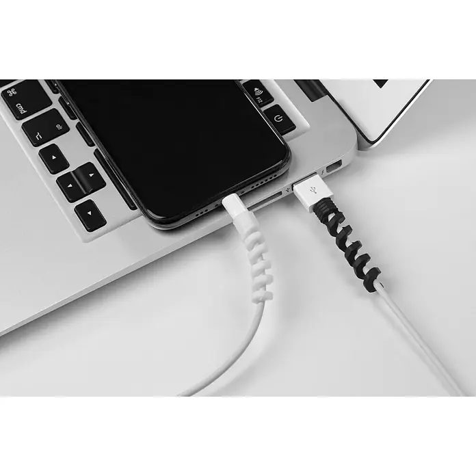 Inofix Protector de cables - Blanco y Negro, 4 ud. - Teléfono inteligente cargándose en una laptop mediante un cable con protectores en espiral.