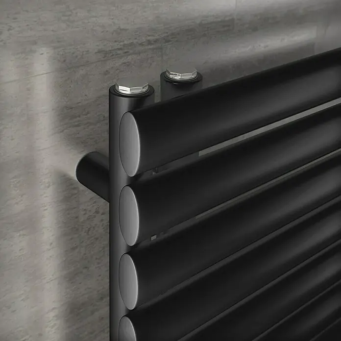 Ximax Designheizkörper Fortuna Open - B x H: 600 x 1.512 mm, Wärmeleistung bei Vorlauftemperatur von 75 °C (D: 50): 832 W, Anthrazit - Detailaufnahme eines schwarzen Handtuchwärmers mit horizontalen Heizstäben und silbernen Befestigungselementen vor einer grauen Wand.