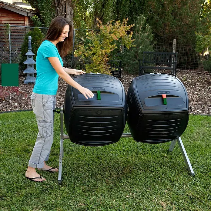 Lifetime Komposter Zwilling - 380 l, 80 x 148 x 111 cm - Eine Frau steht neben zwei schwarzen Lifetime-Kompostbehältern auf einem Rasen. Ideal für die Gartenarbeit, um organische Abfälle zu recyceln.